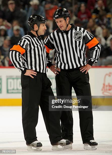 Referees Tim Peel and Brad Watson talk as the Colorado Avalanche face the Calgary Flames at the Pepsi Center on November 24, 2007 in Denver,...