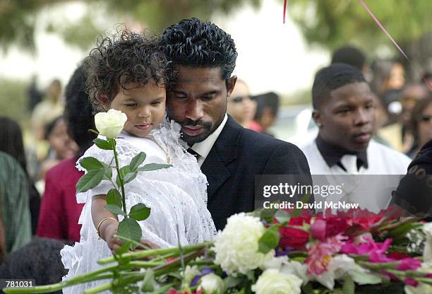 Avinesh Kumar holds his 18 month-old daughter Preshilla Caprice Kumar as she places a rose her mother's coffin October 20, 2000 in San Diego, CA...