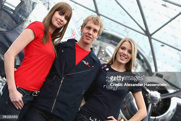 Sebastian Vettel of the Torro Rosso Formula One Team poses with models during the Puma Red Bull Collection Launch at the Hangar 7, on November 27,...