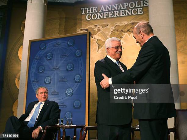 President George W. Bush watches as Palestinian Authority President Mahmoud Abbas and Israeli Prime Minister Ehud Olmert shake hands during a joint...