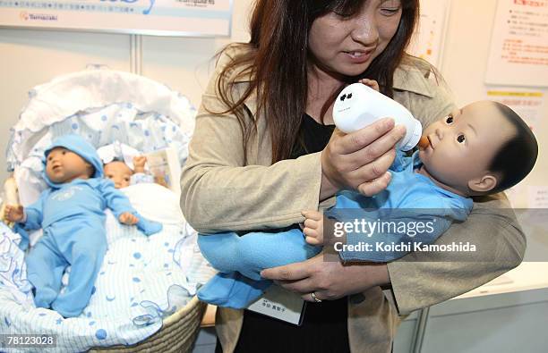 Woman holds the child-care simulation robot "My Baby 2" by Realityworks during the 2007 International Robot Exhibition at Tokyo Big Site on November...