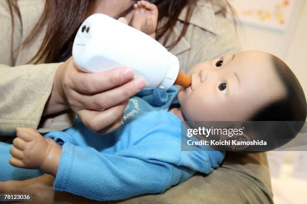 Woman holds the child-care simulation robot "My Baby 2" by Realityworks during the 2007 International Robot Exhibition at Tokyo Big Site on November...