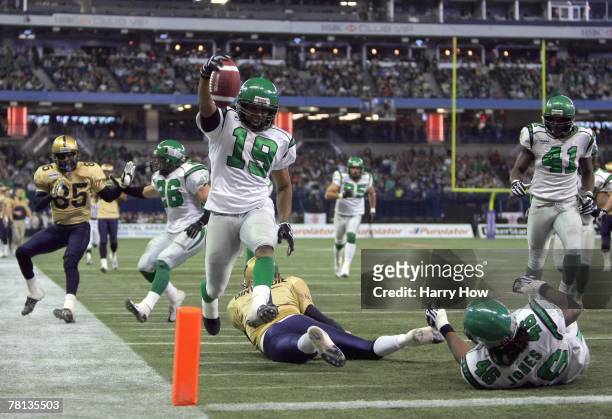 James Johnson of the Saskatchewan Rough Riders jumps over a fallen Ryan Dinwiddie after his interception to score a touchdown to tie the game 7-7...