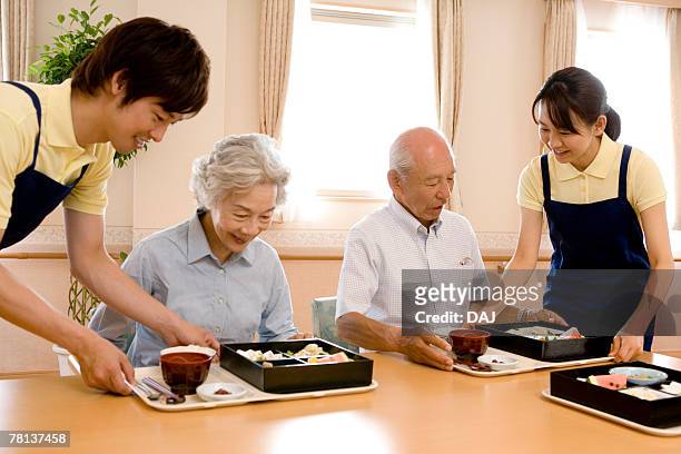 nurses serving lunch for senior man and woman, smiling - elderly care japanese photos et images de collection