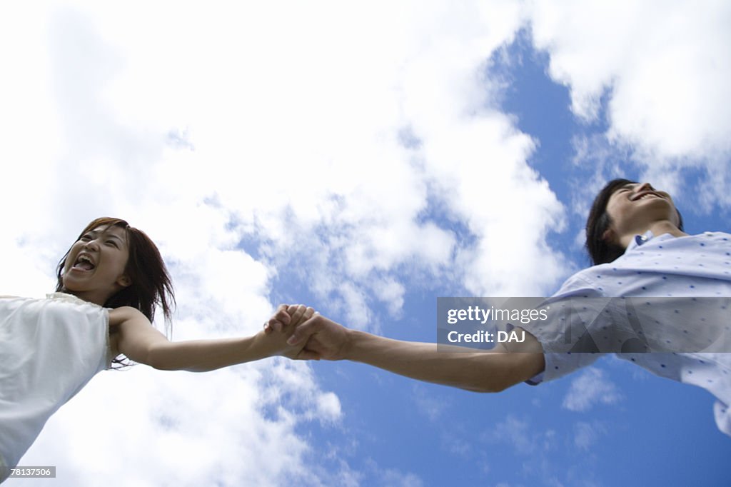 Young couple running under the sky, hand in hand, Saipan 