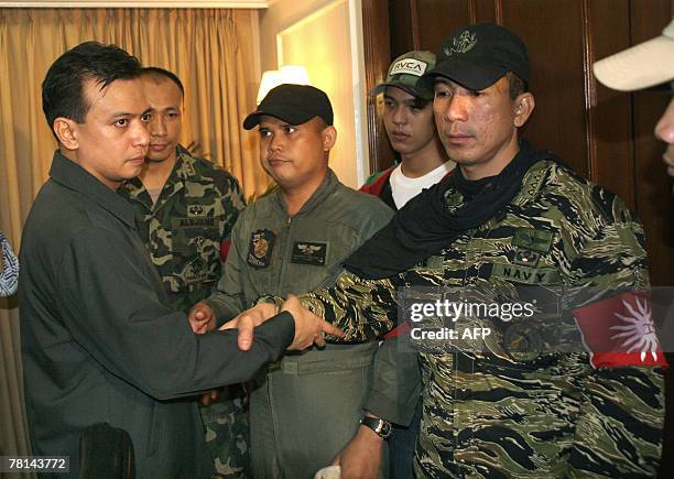 Rebel Philippine Senator Antonio Trillanes joins hands with rebel officer Lieutenant Senior Grade James Layug and others during their surrender to...
