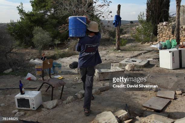 Right-wing Jewish youth carries water as settlers establish themselves in an abandoned Arab house where they are building their new unauthorised...