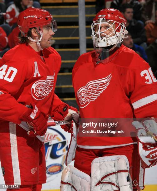 Henrik Zetterberg talks to teammate Chris Osgood of the Detroit Red Wings before a face off during an NHL game against the Calgary Flames on November...