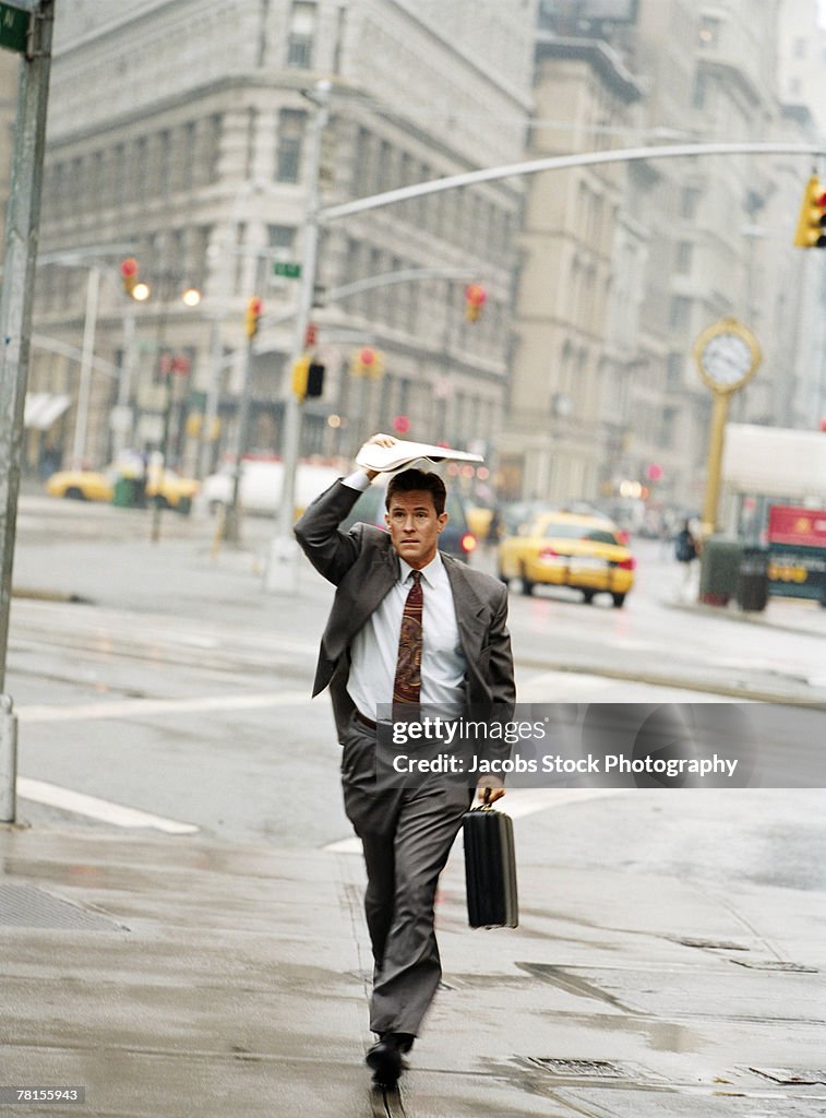 Businessman shielding himself during a downpour