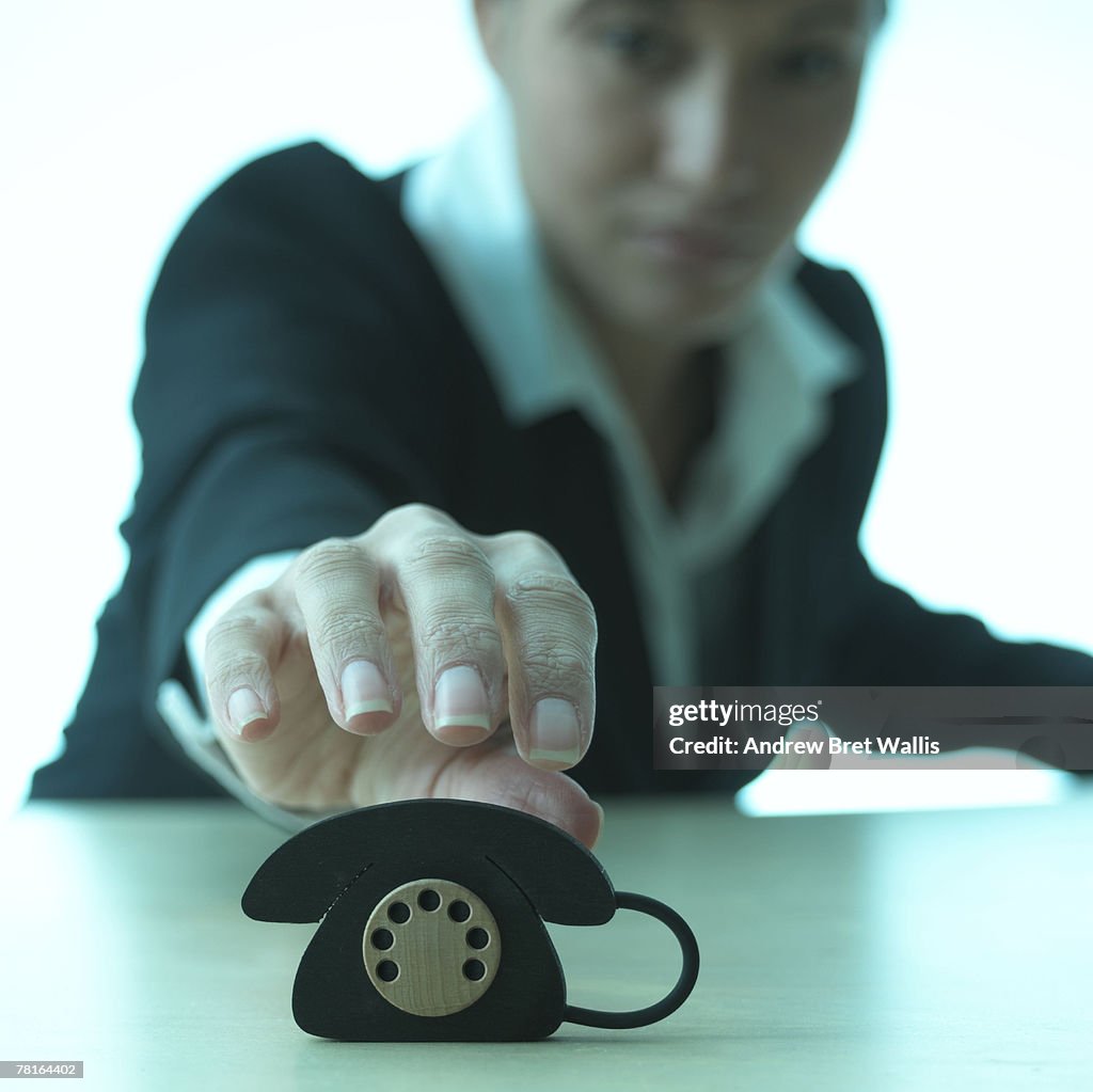 Businesswoman with a miniature telephone