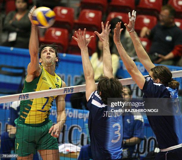 Brazilian volleyball star Gilberto Godoy Filho "Giba" spikes the ball against Argentina's Diego Stepanenko and Lucas Chavez during their match at the...