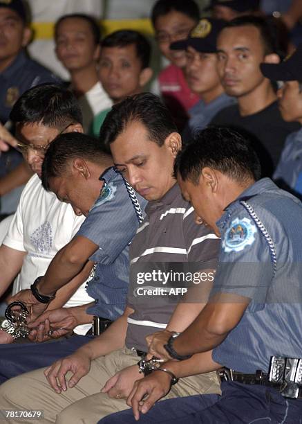 Arrested leaders of the failed mutiny Senator Antonio Trillanes and Brigadier General Danilo Lim are handcuffed to police escorts as the group face...