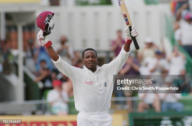 Trinidadian cricketer Brian Lara of the West Indies cricket team raises his bat and helmet in the air as he bats for West Indies against England...