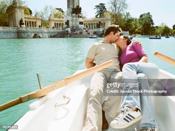 young couple kissing on a rowboat. - parque del buen retiro stock pictures, royalty-free photos & images