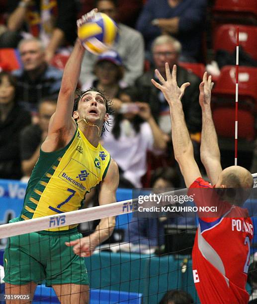 Brazilian volleyball star and captain Gilberto Godoy Filho "Giba" smashes the ball over Russian defender Semen Poltavskiy during their match at the...