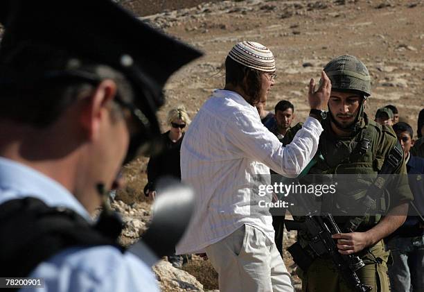 Jewish settler argues with an Israeli soldier trying to prevent a demonstration of international and local peace activists calling for the free...