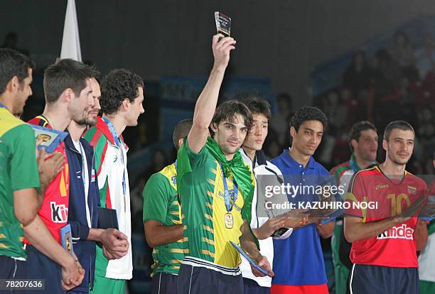 Brazilian volleyball star Gilberto Godoy Filho "Giba" holds up the Most Valuable Player trophy during an award ceremony of the FIVB Men's World Cup...