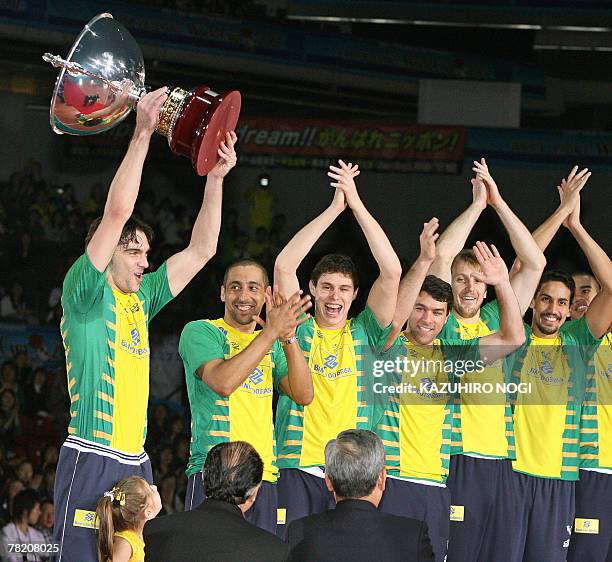 Brazilian volleyball team captain Giba holds up the champions trophy while his teammates clap during an award ceremony at the FIVB Men's World Cup...