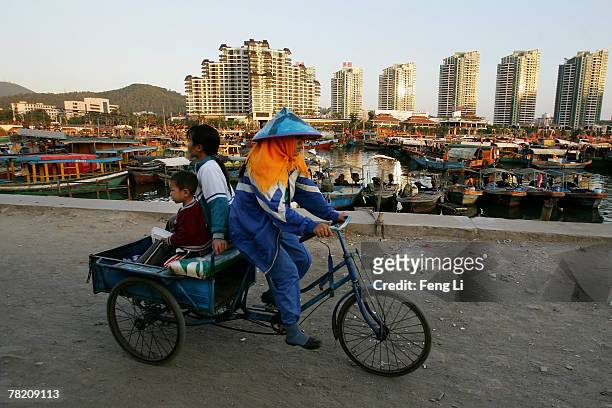 Woman and child rides in the back of a tricycle in a small fishing village near Sanya Harbor on November 30, 2007 in Sanya of Hainan province, China....