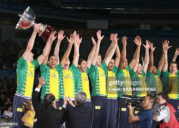 Brazilian volleyball team captain Giba holds up the champions trophy while his teammates clap during an award ceremony at the FIVB Men's World Cup...
