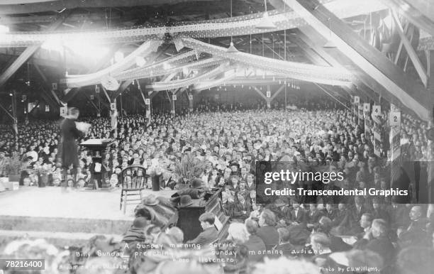 American evangelical preacher Billy Sunday delivers a sermon to some 6000 attendees at a revival meeting, Bloomington, Illinois, late 1907 or early...