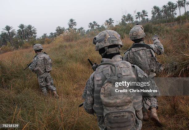 Soldiers with the 4th Stryker Brigade, 2nd Infantry out of Ft. Lewis, Washington, traverse fields on the way to conducting house to house searches...