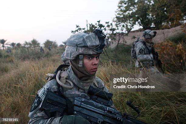 Soldiers with the 4th Stryker Brigade, 2nd Infantry out of Ft. Lewis, Washington traverse fields on the way to conducting house to house searches...