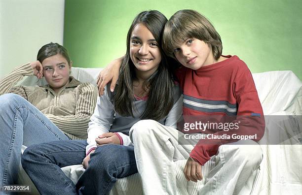 young boy embracing girl while other in the background is looking jealous - claudia neidig stock-fotos und bilder