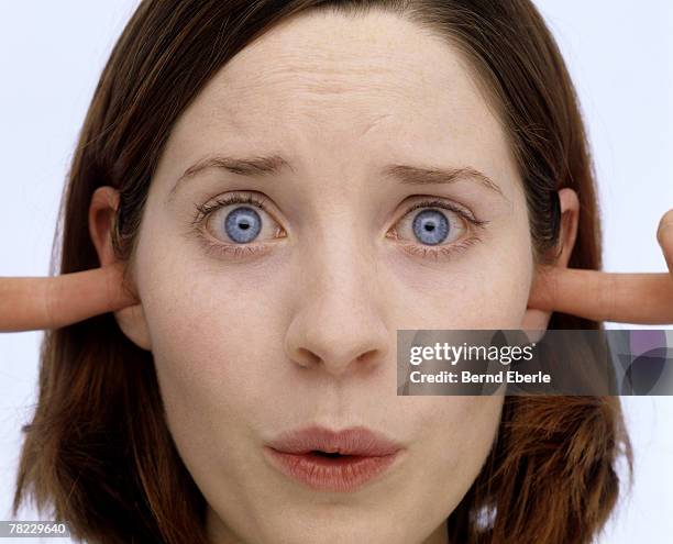 young woman putting her fingers into the ears - woman fingers in ears stock pictures, royalty-free photos & images