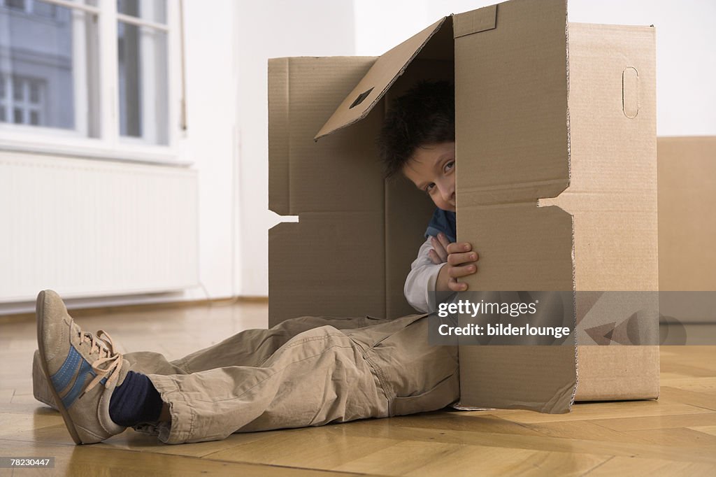 Young boy hiding in moving box