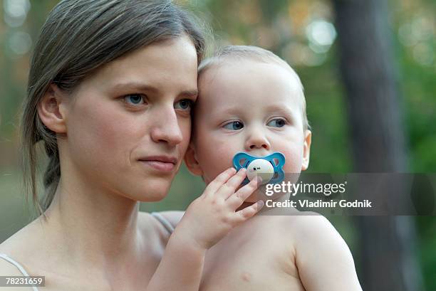 serious looking mother with little baby on her arm - embarazo de adolescente fotografías e imágenes de stock