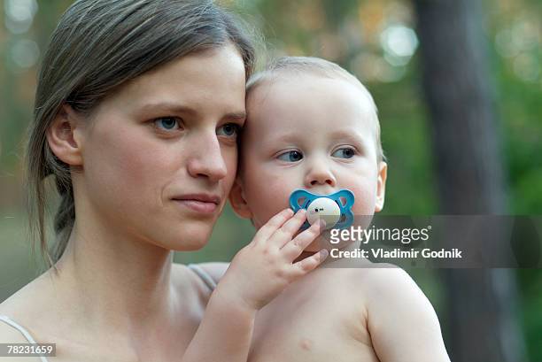 serious looking mother with little baby on her arm - teen pregnancy stock pictures, royalty-free photos & images