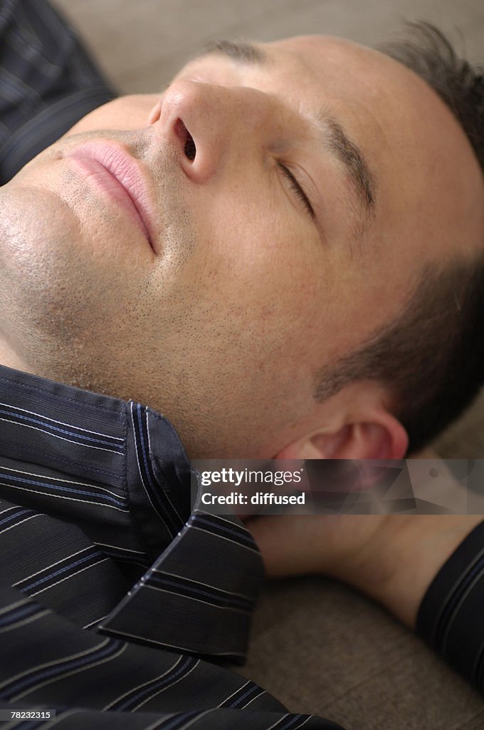 Close-up of young man dozing on floor with eyes closed