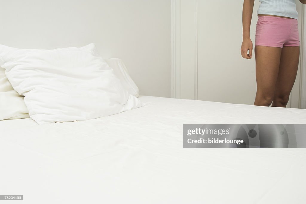 Detail of young woman standing near bed