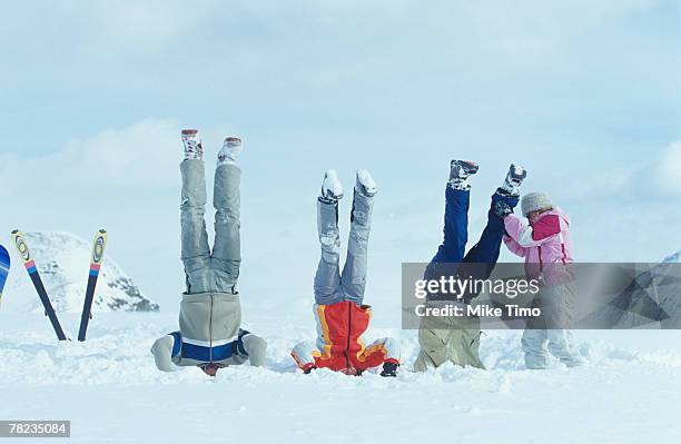 group of three friends doing head stand in snow - apres ski stock pictures, royalty-free photos & images