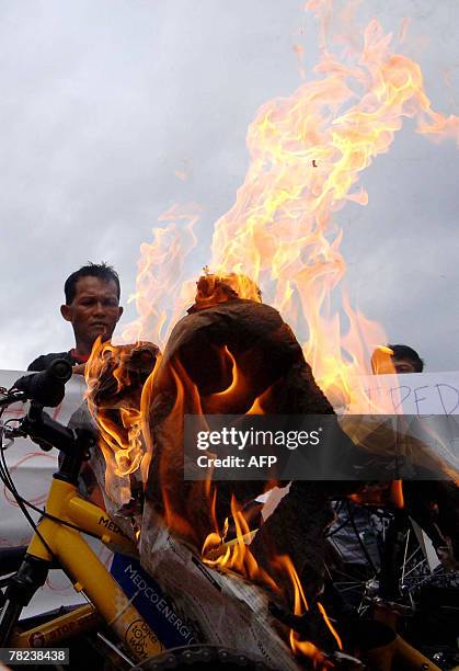 Indonesia's mud-volcano victims set fire on a placard during a demonstration near the venue of the UN Climate Change Conference 2007 in Nusa Dua, on...