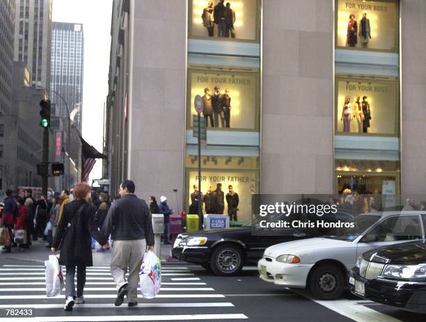 Shoppers carry merchandise bags across Fifth Avenue November 20, 2000 in New York City. Retailers all over the country are preparing for the Friday...