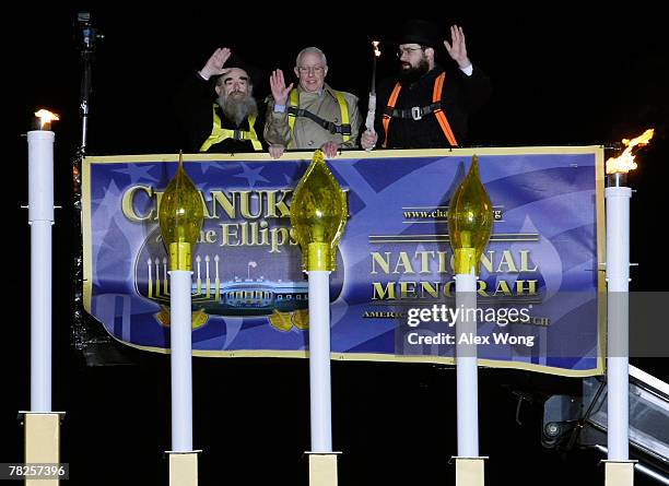 Rabbi Abraham Shemtov, U.S. Attorney General Michael Mukasey, and Rabbi Levi Shemtov wave after they lit the National Menorah during a ceremony at...