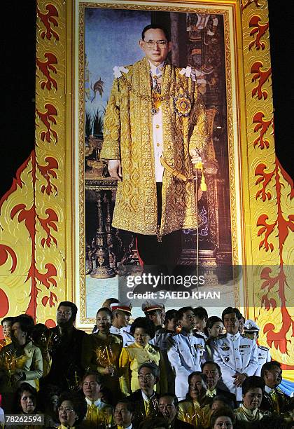 Thai military and civil officials stand under a huge portrait of King Bhumibol Adulyadej to celebrate his birthday in front of the famous Grand...