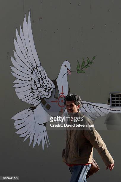 Palestinian man passes a wall painting by elusive British graffiti artist Banksy December 5, 2007 on a shop wall in the biblical city of Bethlehem in...
