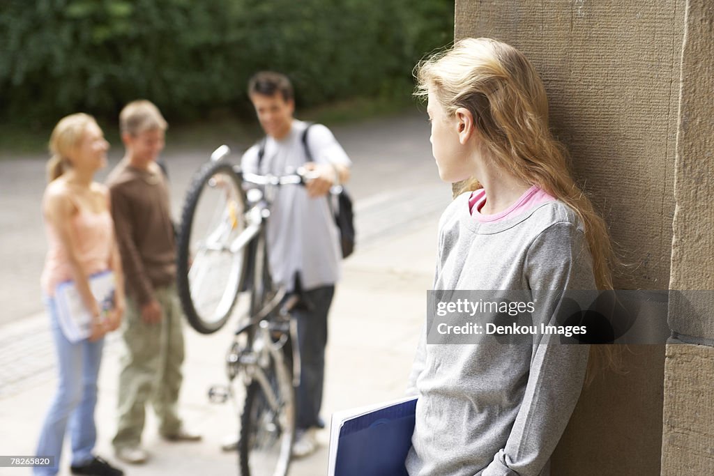 A group of friends chat while a girl looks on.