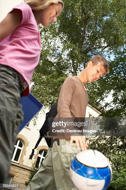 a low angle view of a teenage boy and girl walking. - soccer dribbling stock pictures, royalty-free photos & images