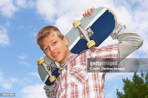 a teenage boy holding a skateboard. - skater boy hair stock pictures, royalty-free photos & images