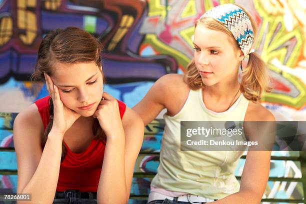 a dejected girl being consoled by another. - girl in tank top stock pictures, royalty-free photos & images