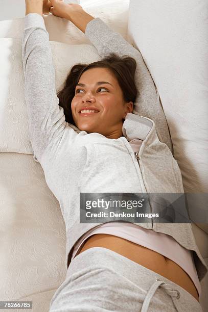 a woman stretching on a couch. - human limb stock pictures, royalty-free photos & images