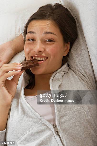 a woman eating chocolate. - indulged photos et images de collection