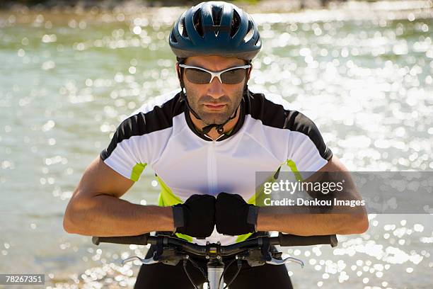 a man sitting on his cycle, river in background - protective sportswear ストックフォトと画像