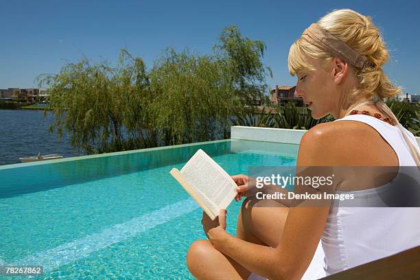 woman reading a book by the pool. - braided buns stock pictures, royalty-free photos & images
