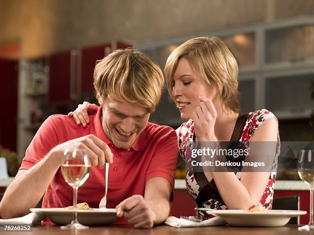 close-up of a young woman whispering into a young man's ear - ear close up women stock-fotos und bilder