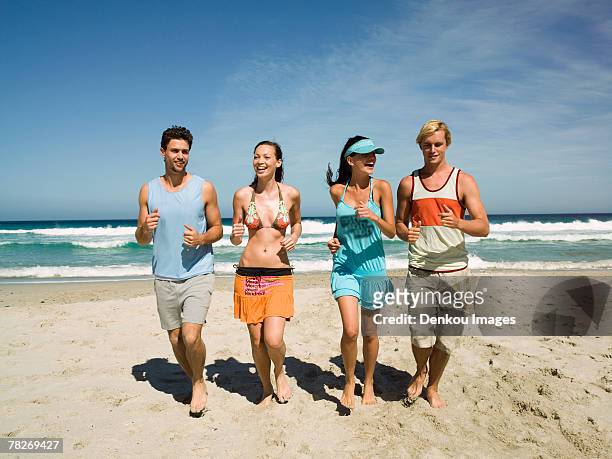 couples jogging on the beach. - swimwear singlet stock pictures, royalty-free photos & images